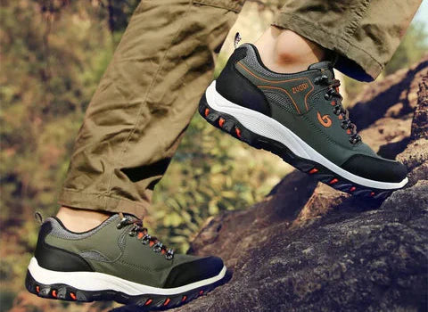 Ein Mann trägt bequeme Wanderschuhe mit ergonomischer Sohle auf einem felsigen Wanderweg.