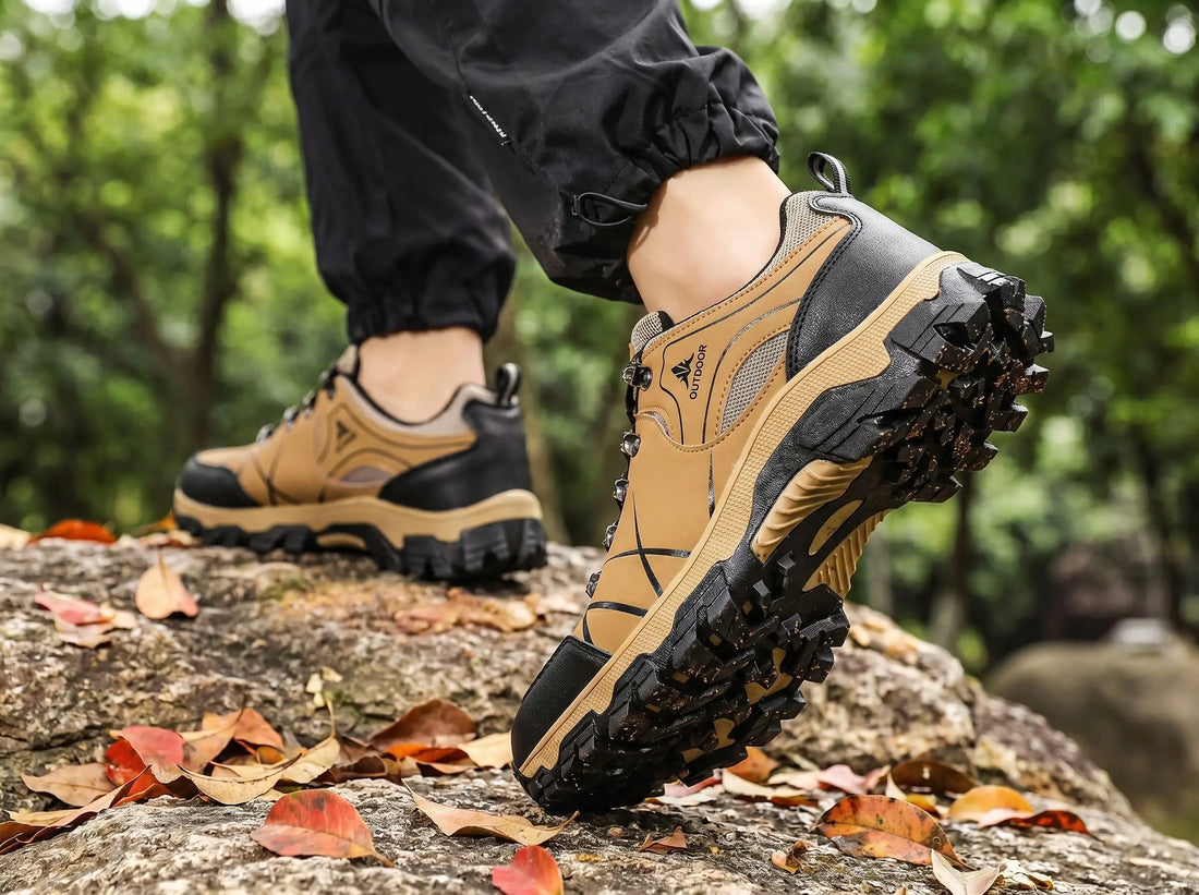 Beige-schwarze orthopädische Wanderschuhe auf einem Felsen mit Herbstblättern – Nahaufnahme der griffigen Sohle und des Obermaterials im Wald